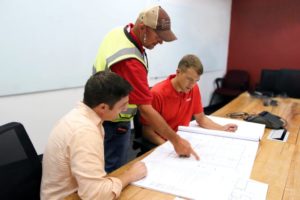 Torc team reviews construction plans for headquarters expansion: From left: Michael Avitabile, Engineering Manager at Torc Robotics, Brian Dodson of Avis Construction, and Michael Fleming, CEO of Torc Robotics, review plans as construction begins.