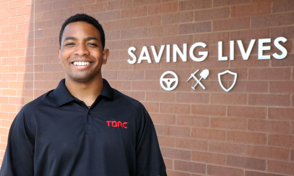 torc team member standing in front of a saving lives sign.