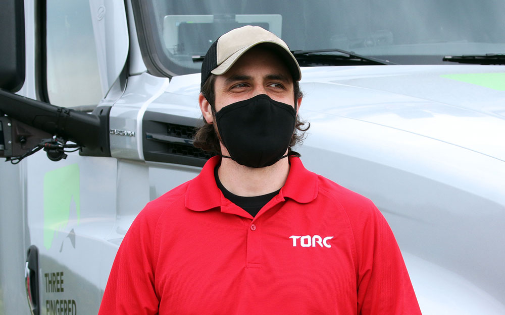 Torc team member wearing a mask and holding a clipboard.